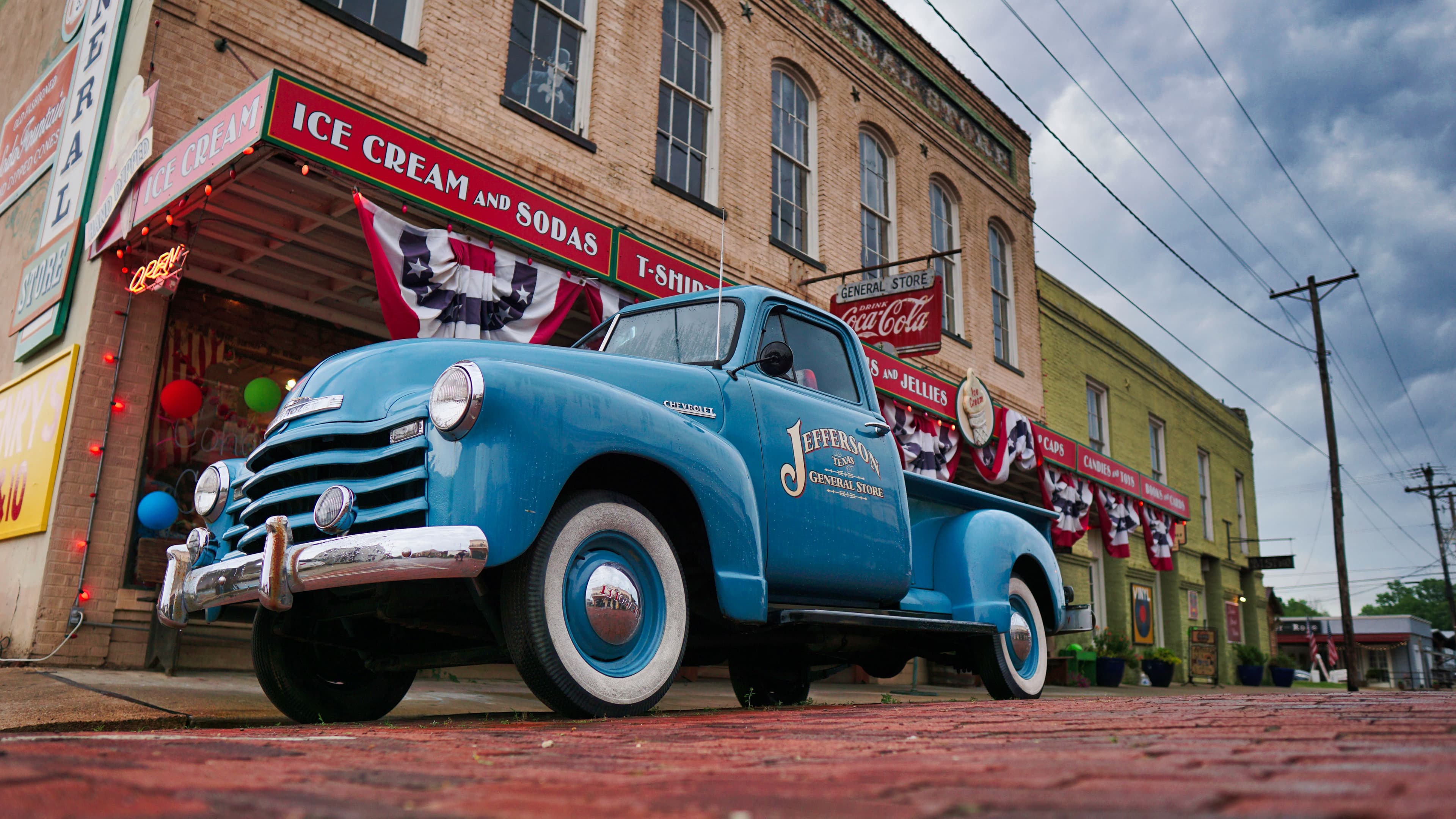 Vintage blue Jefferson General Store truck parked outside the store on the historic brick street